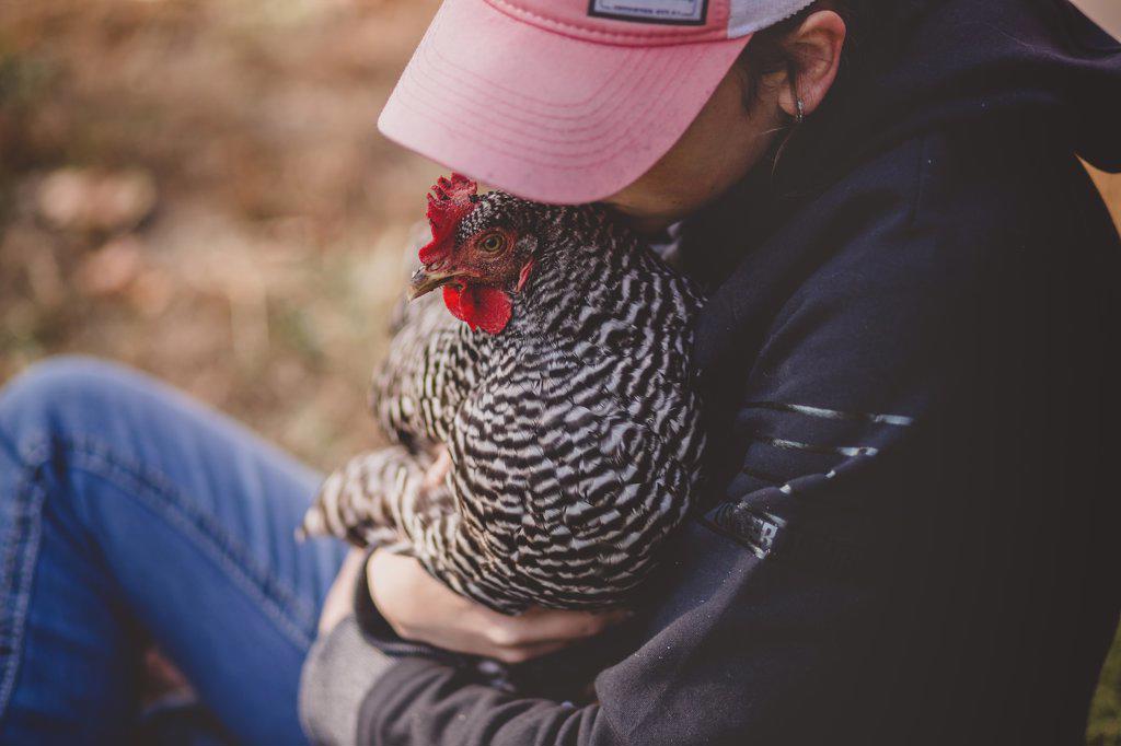 Teen girl holding chicken and kissing her