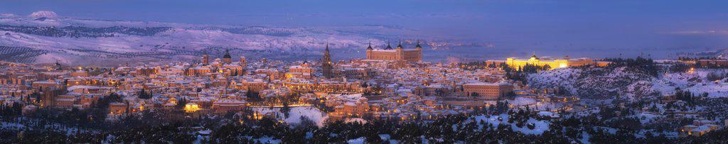 Snowy old town with castle on hill at sunset and illuminated streets