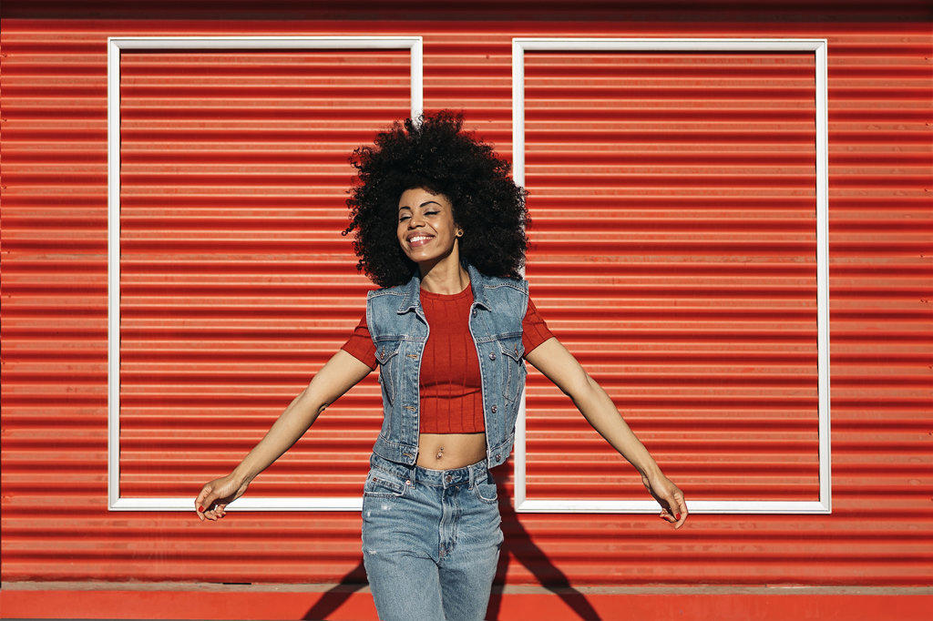 Young afro woman posing over a red background