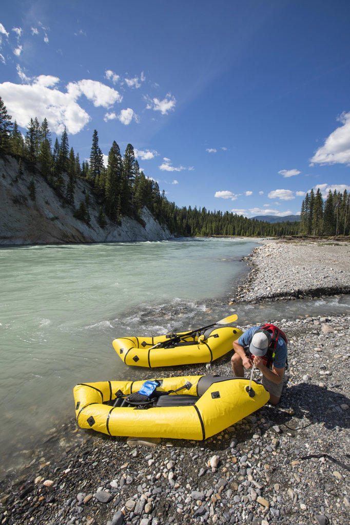Inflating raft using lungs at the rivers edge, B.C. Canada.