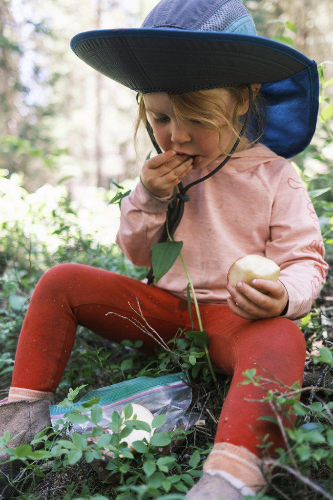 Girl eating an apple in the forest, Colorado