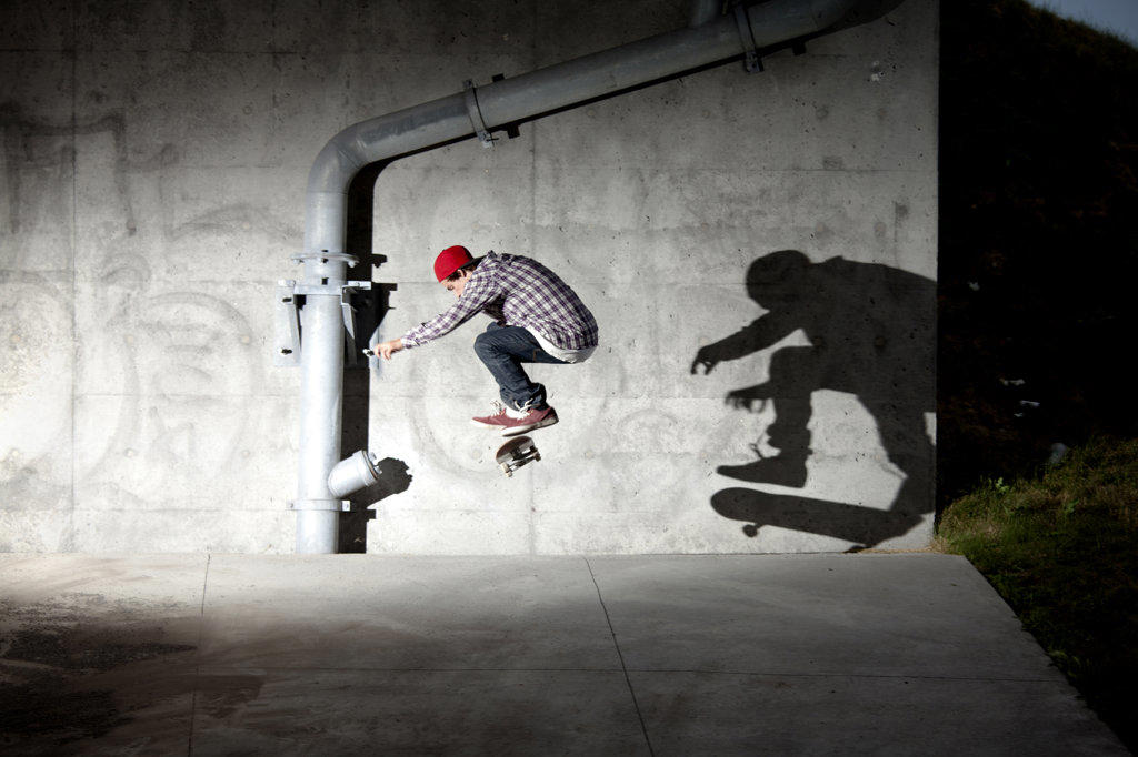 Skateboarder skating under overpass at night