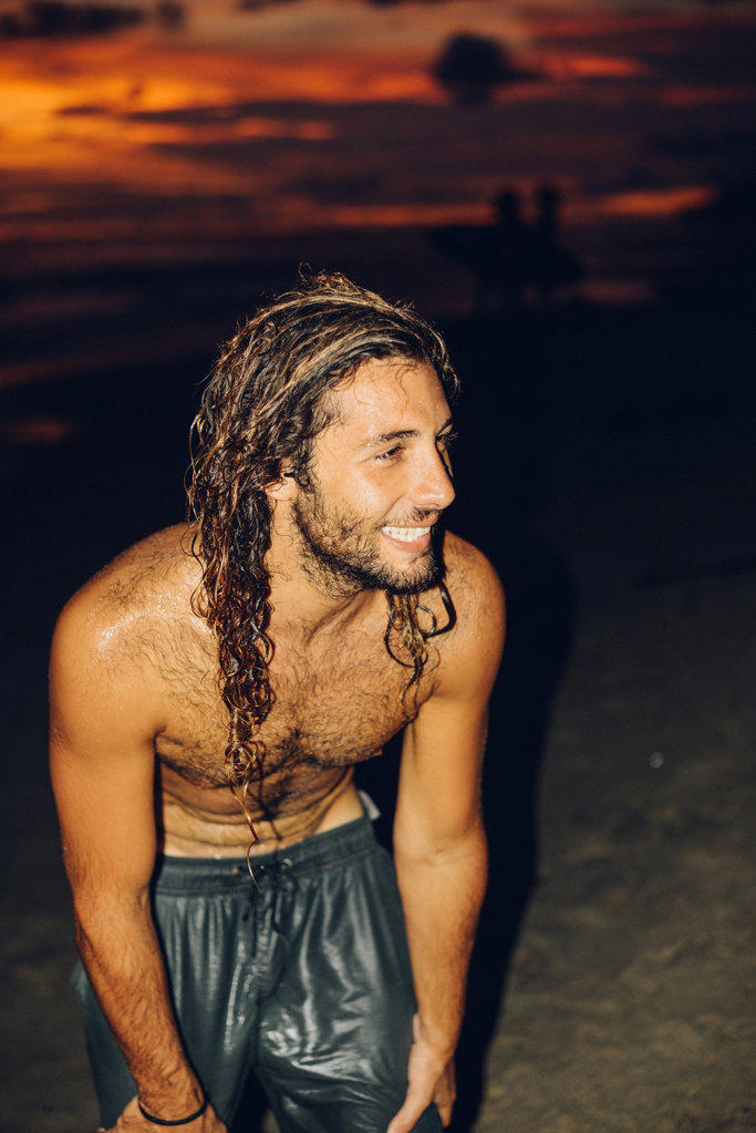 a long hair boy smiling after surfing