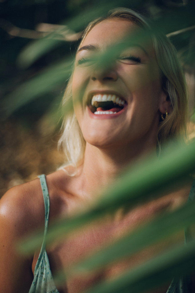 blond girl smiling behind plants in the jungle