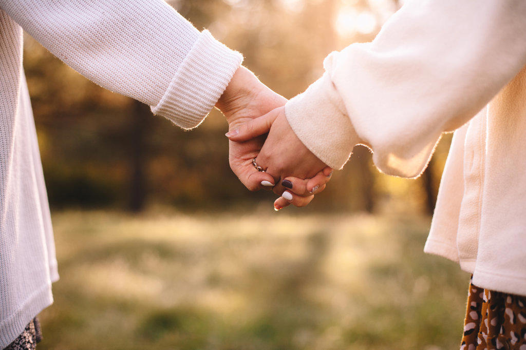 Close up of lesbian couple holding hands while standing outdoors