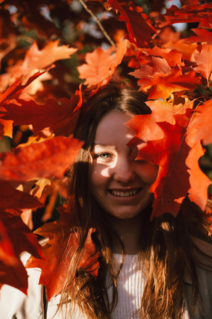 Portrait of smiling teenage girl standing among red leaves in autumn