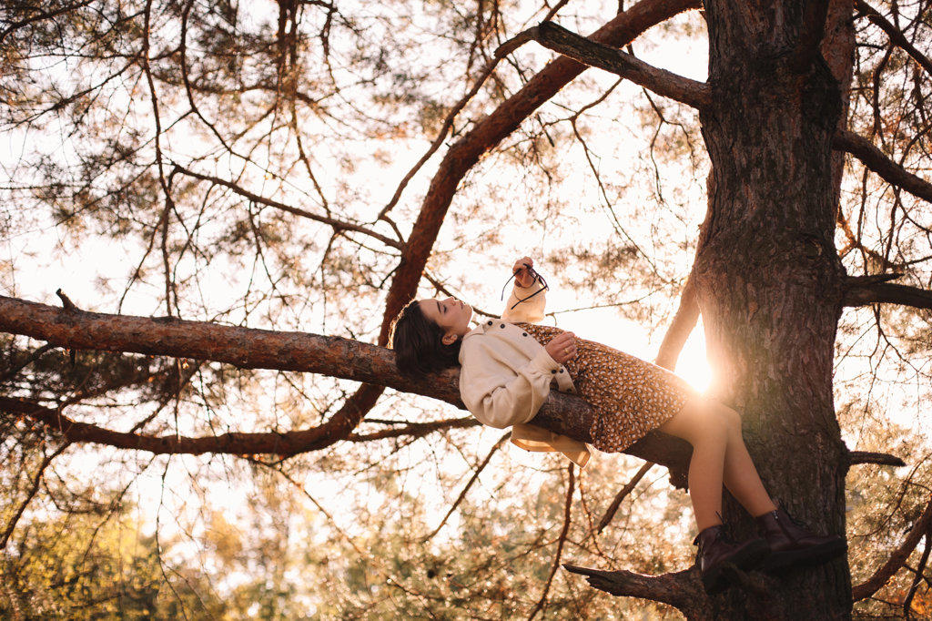 Teenage girl lying on pine tree branch in forest