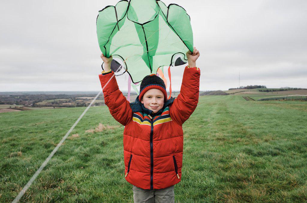 boy happily holding a kite on a windy day outdoors