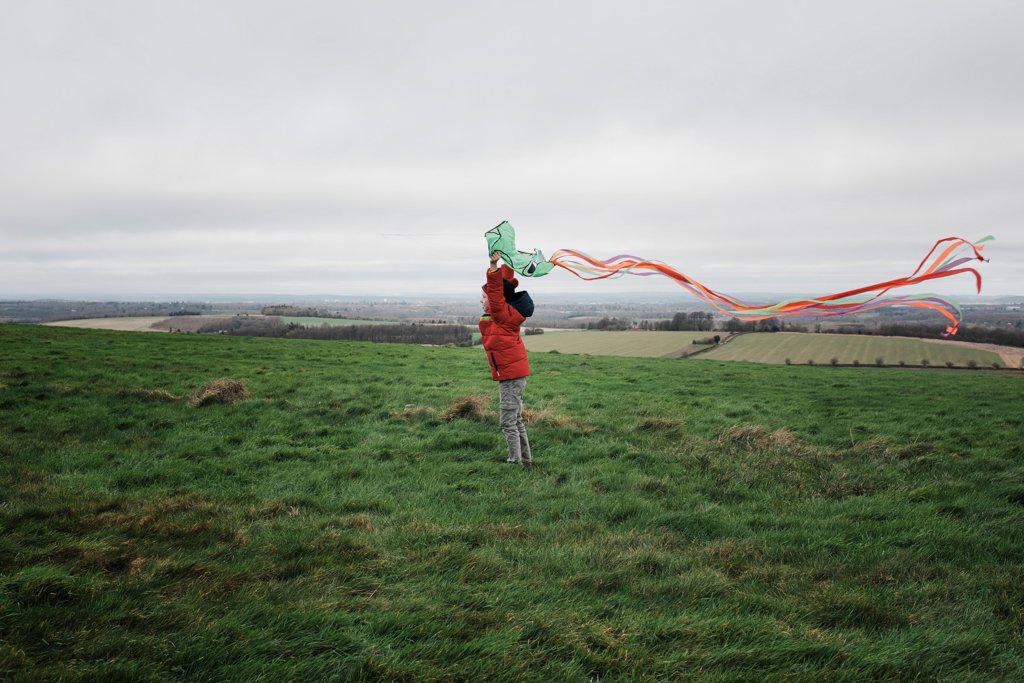 boy flying a kite in a windy field in winter