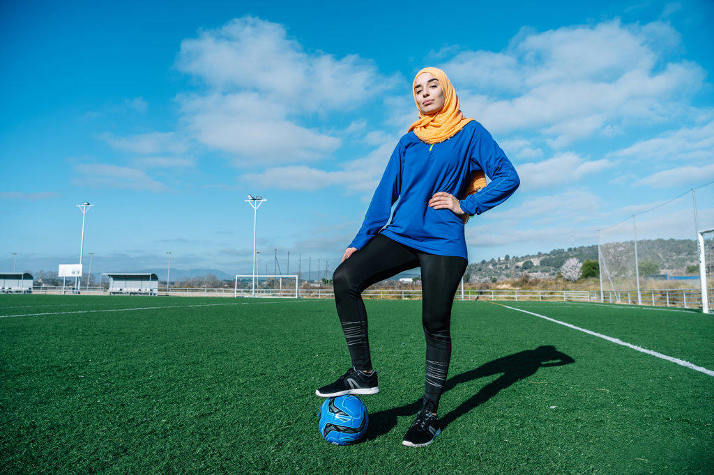 Arab female football player with ball on field