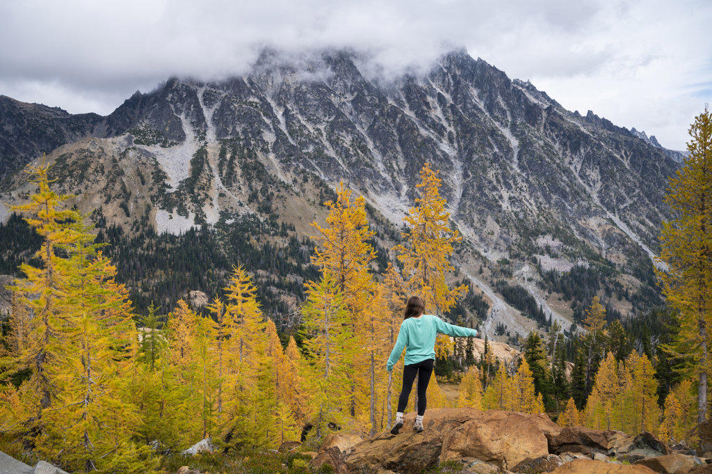 Fit female posing in a forest of golden larches in the fall