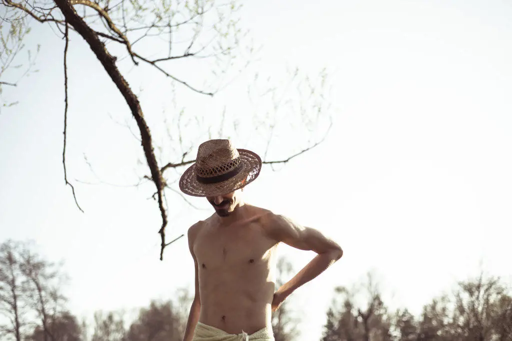 Healthy muscular lean young man wearing hat in nature