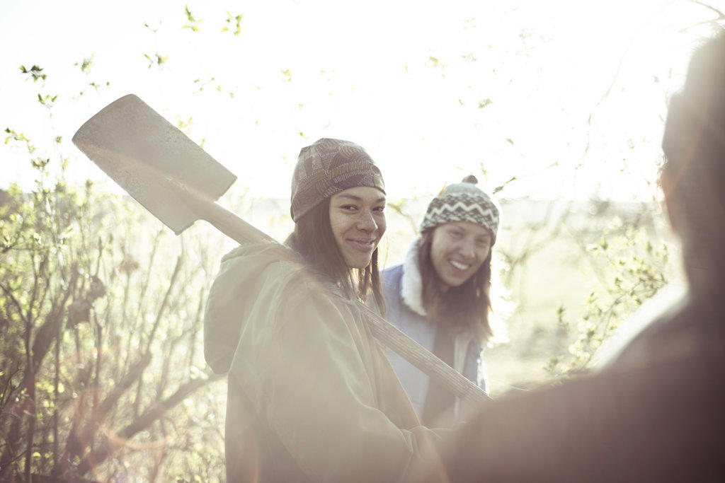 Gypsy person with shovel smiles with friend on spring afternoon