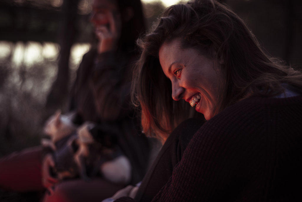 smiling young woman with friends and puppies in background fireside