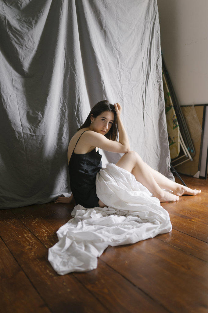 Woman in a nightgown sitting on the floor with a white sheet