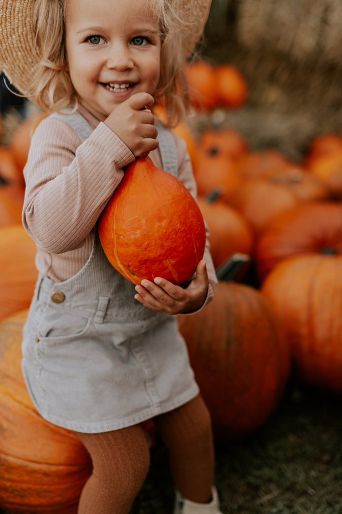 portrait of a little girl on a farm who holds a pumpkin in her hands