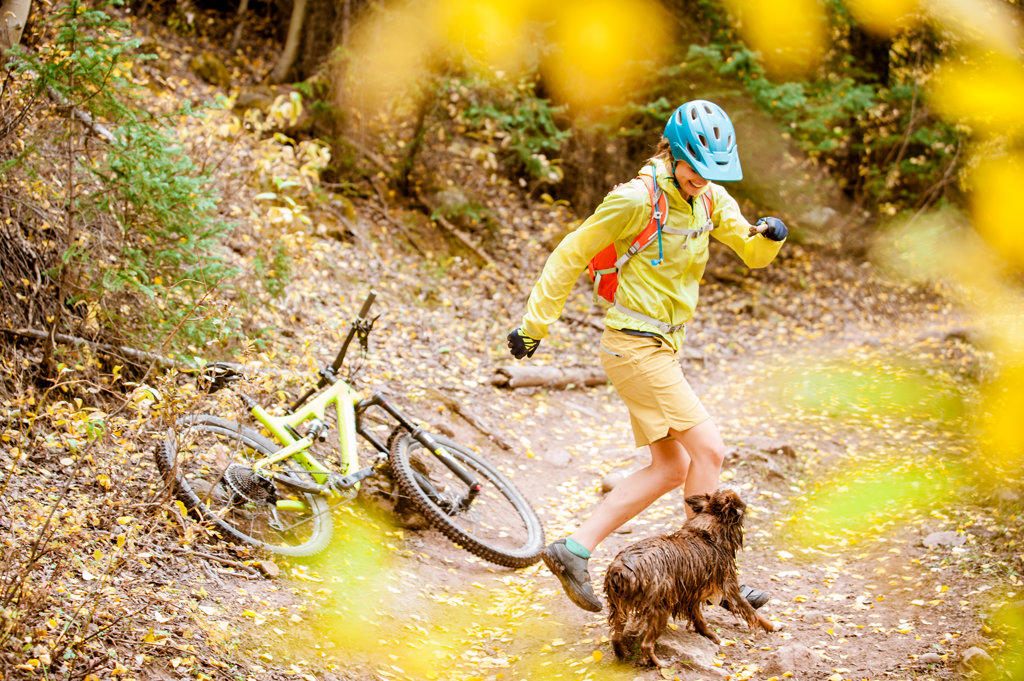 Young woman mountain biking with her dog in the fall