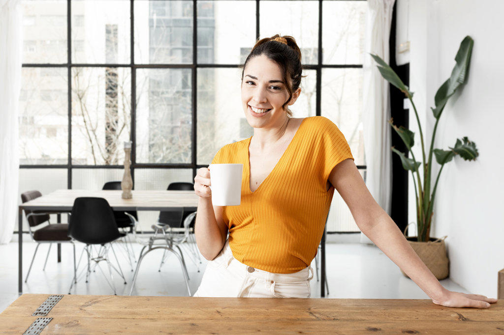 Smiling woman drinking coffee early in the morning