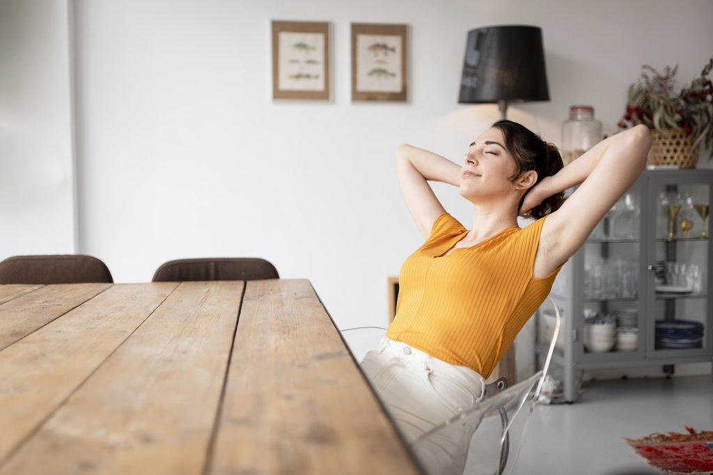 Relaxing woman sitting at dining table at home relaxing