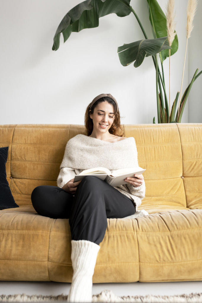 Beautiful girl on a sofa reading a book