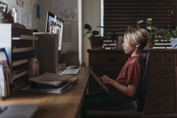 School aged boy learning online by video chat during homeschool