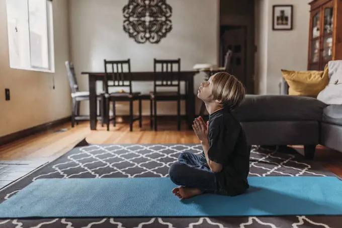 School-age boy doing yoga in living room during isolation