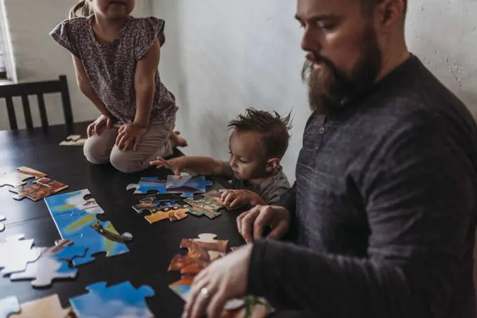 Family with young children completing puzzle at home during isolation