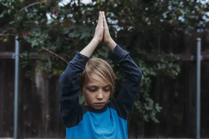 Young boy doing yoga in yard during isolation