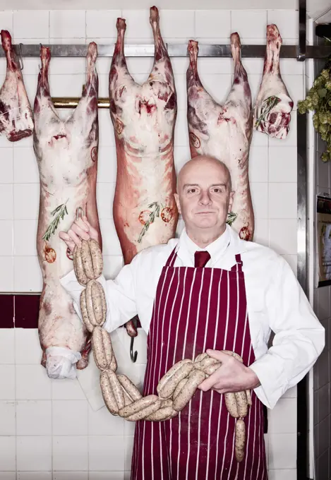 Butcher holding sausage in shop in England