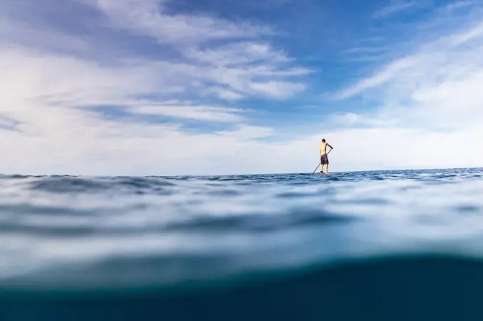 Stand up paddler paddles solo in the ocean of hawaii