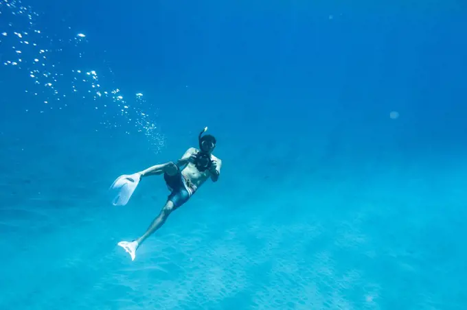 A male snorkeler shoots photos underwater in oahu, hawaii