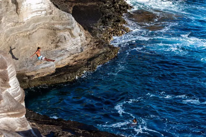 Male cliff diver dives towards the ocean in oahu, hawaii