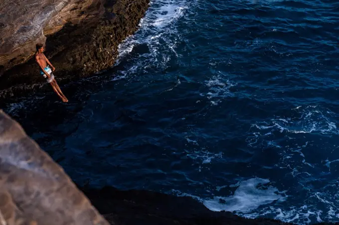 male cliff diver in action at the ocean cliffs of oahu, hawaii