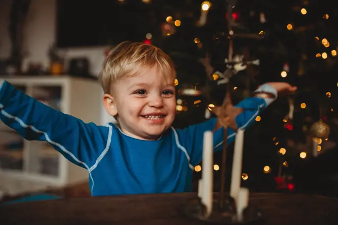 Happy boy smiling at home with a Christmas tree behind him