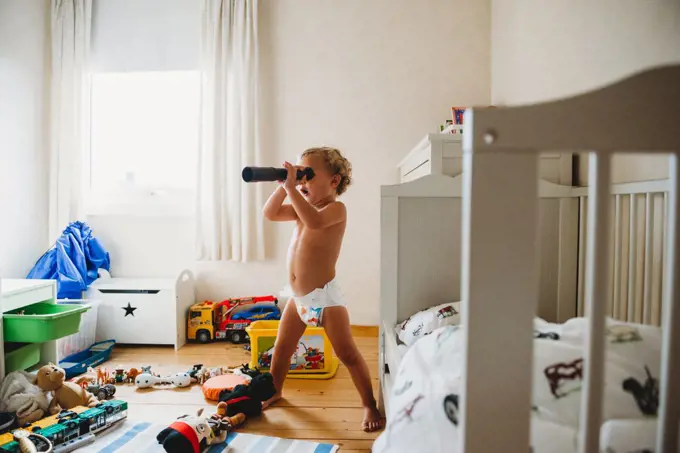 Child in diapers playing in his messy room pretending he's a pirate