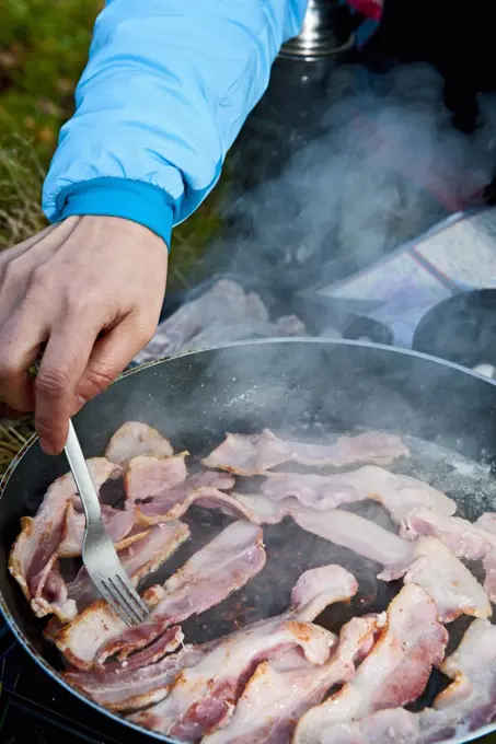 woman frying bacon during picnic in south Wales