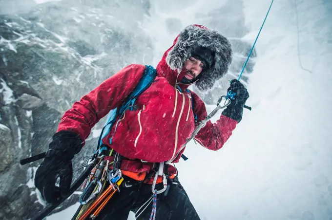 A male ice climber pulls a rope after climbing and rappelling a route