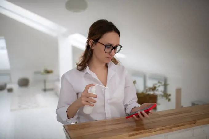 Young woman disinfecting smartphone at home