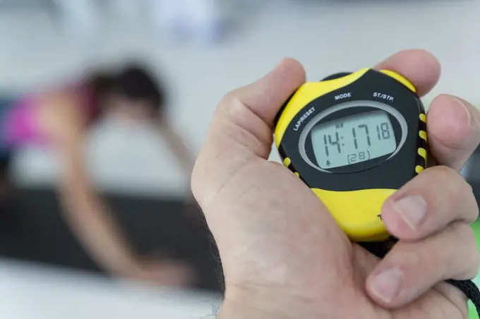 a physical trainer times a physical test, a stopwatch in hand
