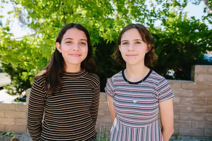 Sisters Wearing Contrasting stripes Offer Polite Smiles To The Camera