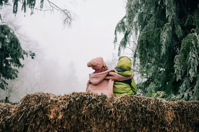 two friends hugging sat outside together enjoying the winter scene