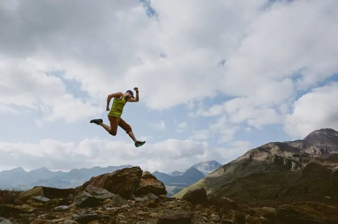 A man jumps into the air in front of mountain landscape