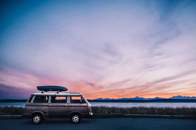 A VW Van is parked in front of puget sound with epic sunset