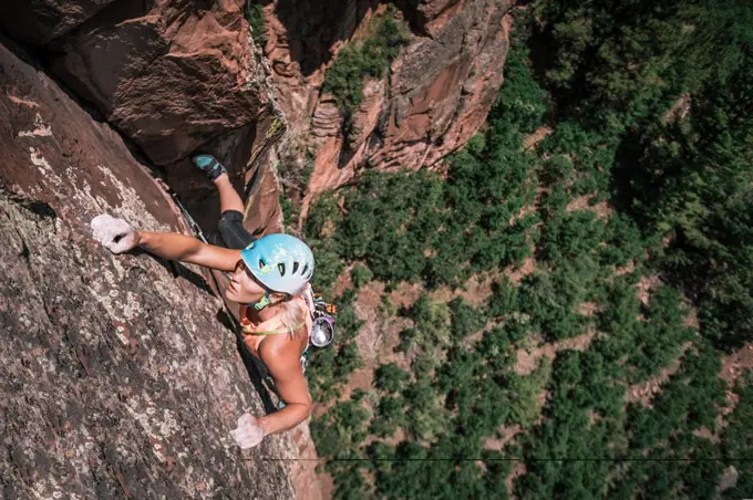 Female climber holds crimpers but stays focused high on the wall