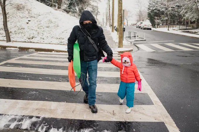 Dad and child crossing the street during snow storm