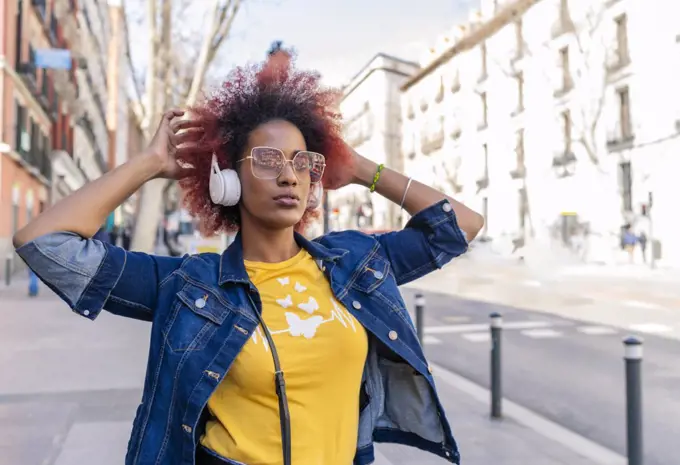 woman with afro hair listening to music with her headphones in the city