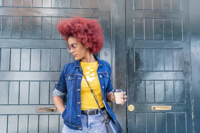 woman with red afro hair having her coffee in the street