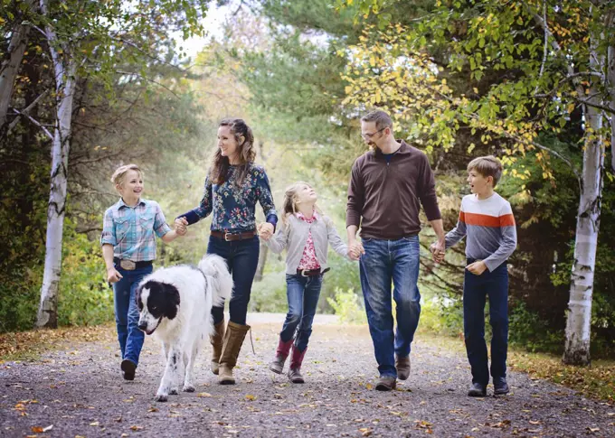Happy family of five walking down country road with big dog.