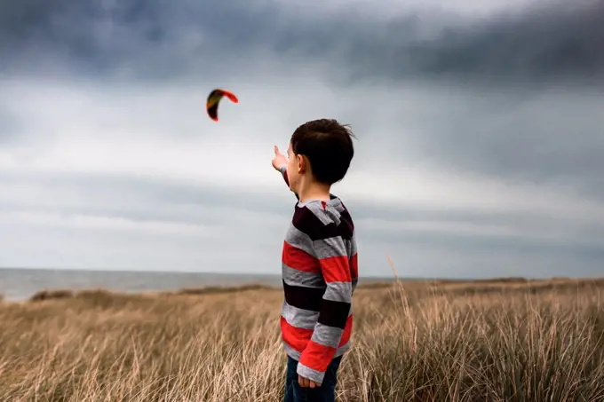 boy pointing to kite surfer in the clouds on a beach in Lake Michigan