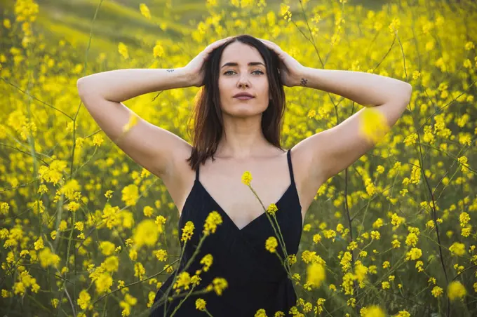 Young woman looking at camera in yellow wildflower field